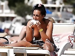 Topless big tits girl has lunch on the beach